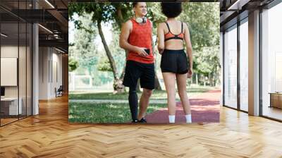 Two friends engage in a lively workout outdoors, embodying strength and unity in fitness. Wall mural