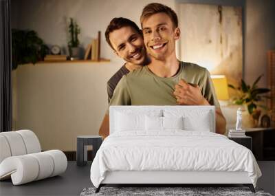 Two men embrace joyfully, cherishing their time together in a cozy living room. Wall mural