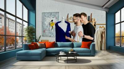 Two men stand beside a mannequin, collaborating on trendy attire in a designer workshop. Wall mural