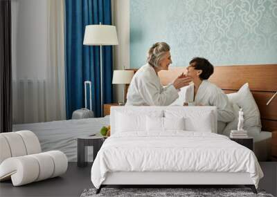 Two senior women, a loving lesbian couple, sit peacefully on top of a bed. Wall mural