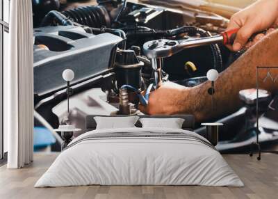 The auto mechanic is fixing the engine of the car with a socket wrench Wall mural