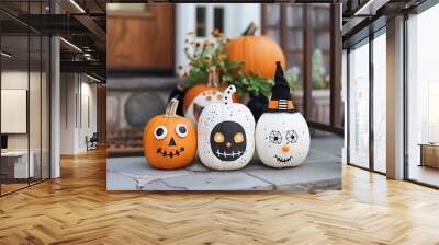 Festive Halloween pumpkins decorated with various spooky faces and designs on a front porch. Wall mural