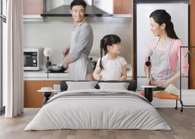 Happy young family cooking in kitchen Wall mural