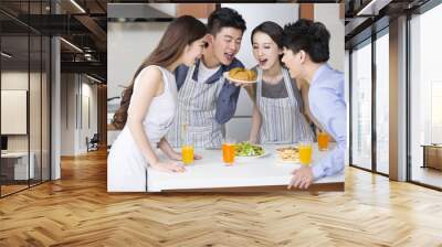 Young couple cooking for their friends in the kitchen Wall mural