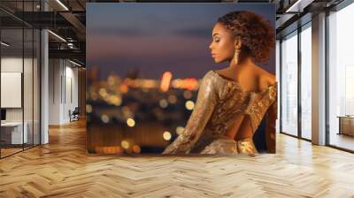 A young model wearing a glamorous evening gown, standing against a city skyline at dusk, embodying sophistication and elegance. Generative AI Wall mural