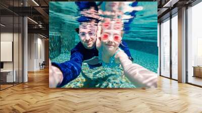 Father and daughter swimming underwater Wall mural