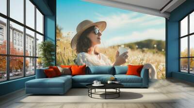 Woman sits and sips coffee amidst beautiful nature. Wall mural