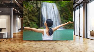 Woman traveler happy at deep forest waterfall. Erawan Waterfall National Park, Kanchanaburi, Thailand. Wall mural