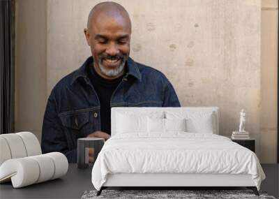 Mature black man in city using cell phone Wall mural