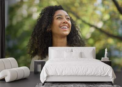 Young black woman smiling happy face at a park looking at sky Wall mural