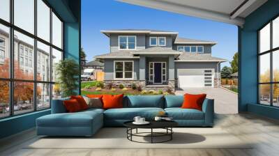 Exterior of new home on bright sunny day with blue sky. Features two car garage, front yard with green grass, and modern design Wall mural