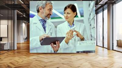 A female and male pharmacist looking at each other while doing inventory. Wall mural