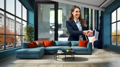 A satisfied businesswoman greets a male colleague before the meeting. Wall mural