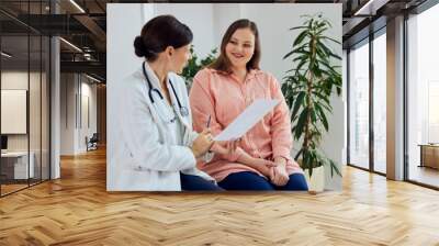 A smiling overweight woman sitting with a female nutritionist during the examination. Wall mural