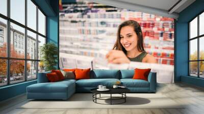 Beautiful woman buying body care products in supermarket. Wall mural