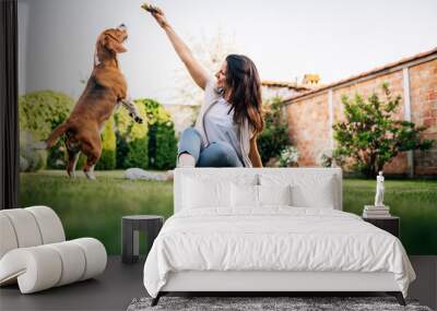 Beautiful woman giving food to dog from her hand. Wall mural