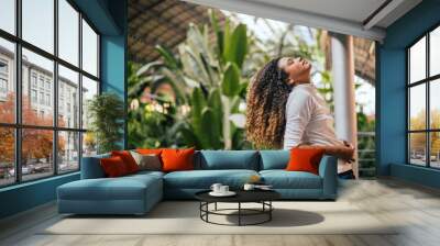 Beautiful woman with afro curly hair posing with head tilted up. Wall mural