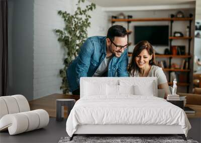 Casual coworkers looking at laptop at modern cozy workplace. Wall mural