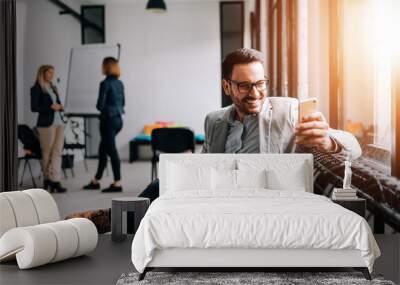 Close-up image of smiling businessman using cellphone in the meeting room. Wall mural