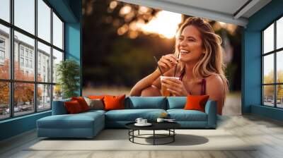 Close-up portrait of a beautiful happy young woman drinking on a beach. Summer vacation concept. Wall mural