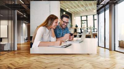 Colleagues working in office and using credit card. Wall mural