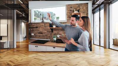 Couple talking about home renovation. Standing in the kitchen and discussing apartment renovation ideas. Wall mural