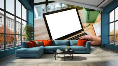 Cropped view of young office worker sitting at table and typing on laptop. Wall mural