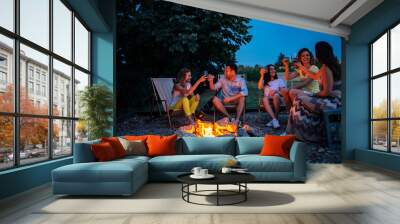 Friendship, happiness, summer vacation, holidays and people concept. Friends having a toast around the bonfire. Wall mural