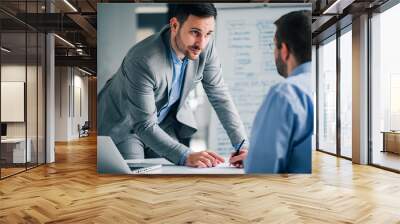 Handsome manager discussing with employee in the office. Wall mural