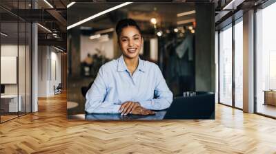 Happy African businesswoman sitting at the office, posing for the camera. Wall mural