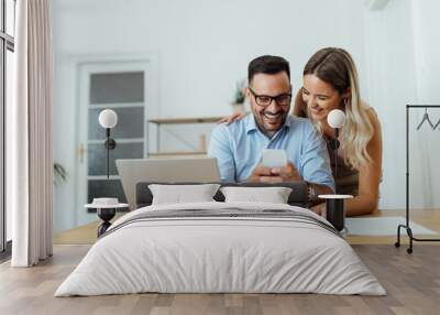 Happy couple looking at smart phone and laughing, portrait. Wall mural