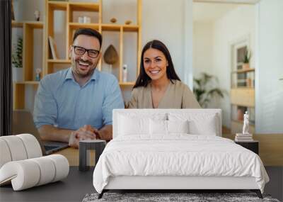 Happy young business woman and handsome man using laptop and notes in their home office. Wall mural