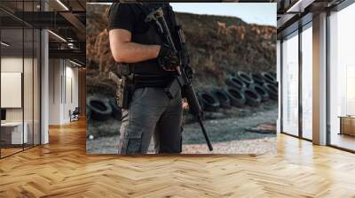 Image of armed man with rifle and gun standing outdoors, close-up. Wall mural