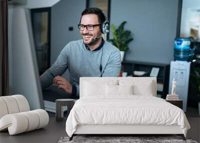 Portrait of a handsome smiling man with headset working on the computer. Wall mural