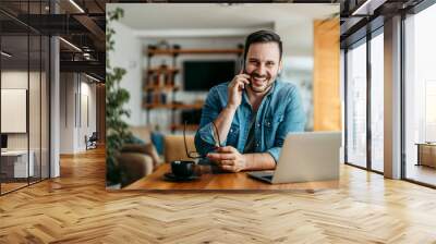 Portrait of a happy casual man talking on smart phone at home office. Wall mural