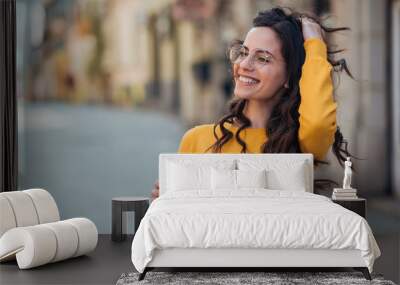 Portrait of a happy young woman in the city holding takeout drink. Wall mural