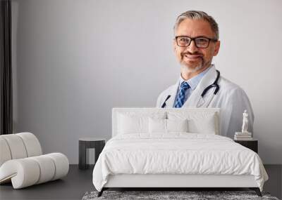 Portrait of a senior doctor with a stethoscope, standing at his workplace. Wall mural