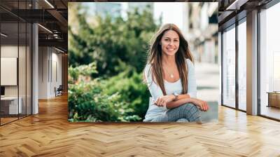 Portrait of a smiling casual brunette, outdoors in the city. Wall mural