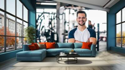 Portrait of a smiling young man in sportswear in the gym, looking at camera. Wall mural