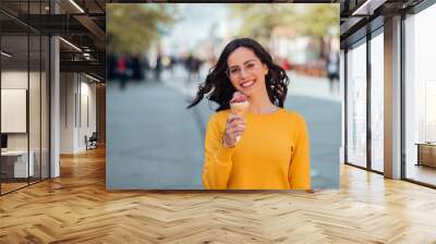 Portrait of a student girl eating ice cream outdoors. Wall mural