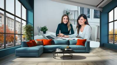 Portrait of a two casual female entrepreneurs working. Looking at camera. Wall mural