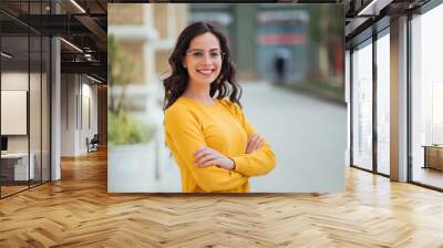 Portrait of a young confident woman outdoors, smiling at camera. Wall mural