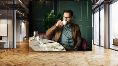 Portrait of elegant man drinking cup of coffee at fancy restaurant. Wall mural