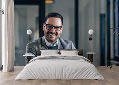 Portrait of happy caucasian man, smiling for the camera while working in the office. Wall mural