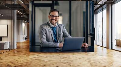 Portrait of lovely caucasian man, preparing his desk for work in the morning. Wall mural