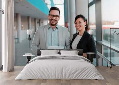 Portrait of two business people standing in office lobby. Wall mural