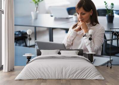 Portrait of young attractive woman at office desk, with laptop. Wall mural