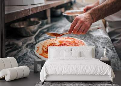 Preparing pizza. Chef's hand adding tomato sauce on pizza dough. Wall mural