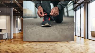 Senior athlete tying shoelaces. Wall mural