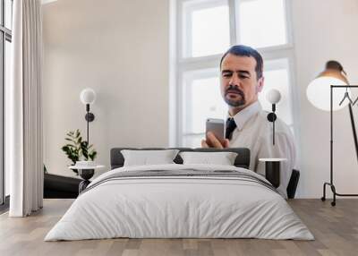 Senior businessman reading a message on his mobile phone in office. Wall mural